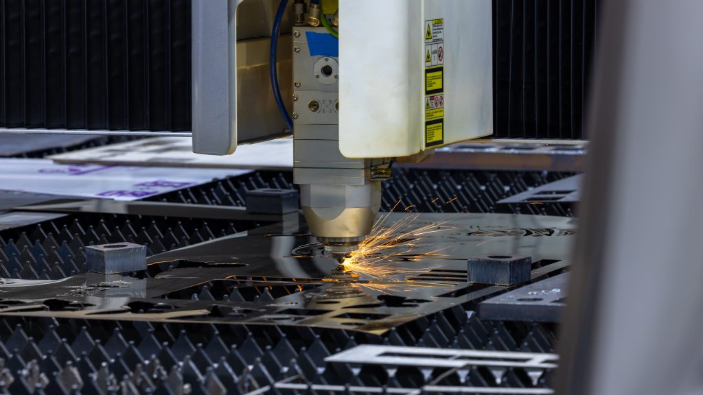 Detailopname van een precisie-laserkop tijdens het lasersnijden aluminium met zichtbare vonken op de snijtafel