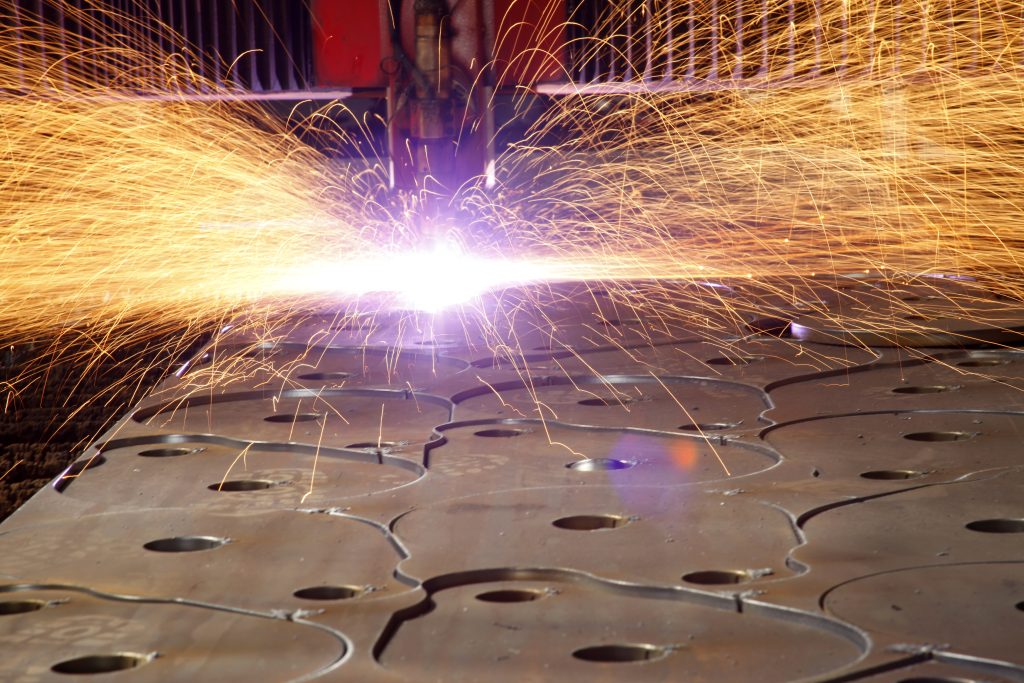 CNC-laser snijdt metalen plaat met vonken, illustratie van verspanen betekenis in de metaalbewerking