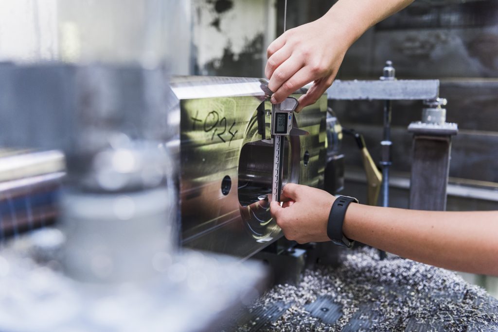 Nauwkeurige meting van een werkstuk met een schuifmaat als onderdeel van professionele kunststof bewerking in de fabriek