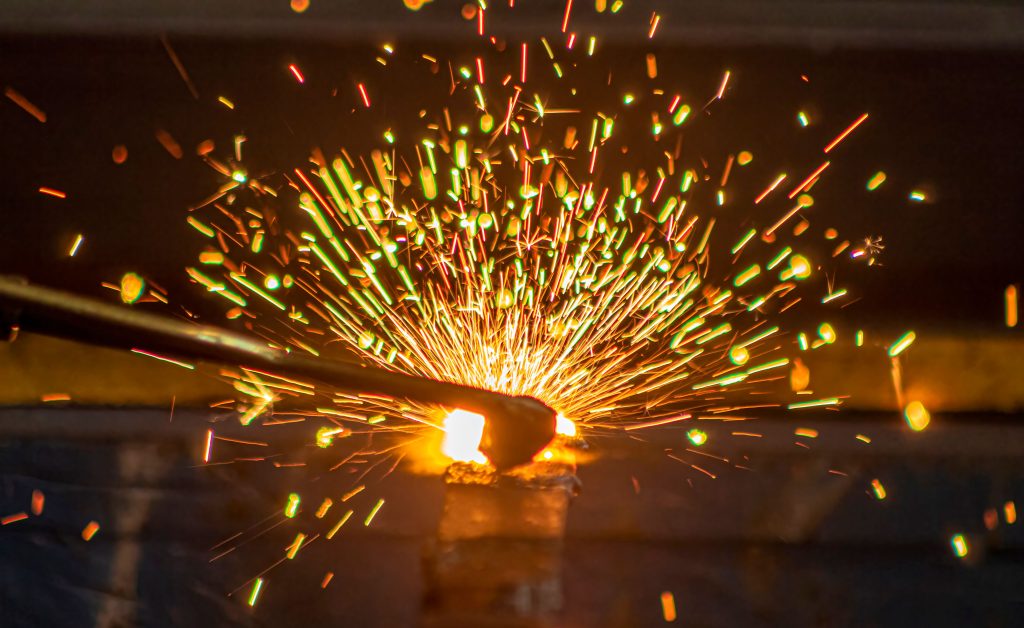 Spectaculair beeld van rondvliegende vonken tijdens het autogeen snijden van metaal in een industriële werkplaats