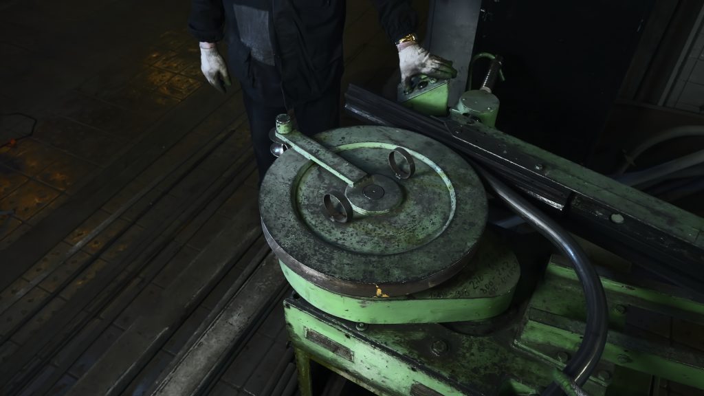 Vakman bedient een industriële buigmachine voor het nauwkeurig aluminium buizen buigen in de werkplaats