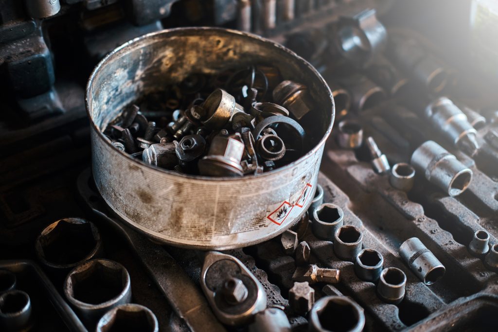 Bakje met diverse bevestigingsmaterialen zoals bouten en persmoeren in een werkplaatsomgeving.