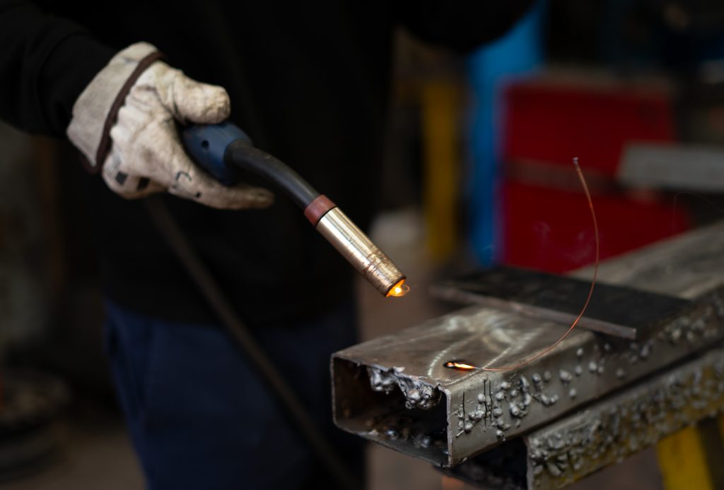 Lasser met beschermende handschoen voert nauwkeurig puntlassen uit op een metalen constructie in de werkplaats